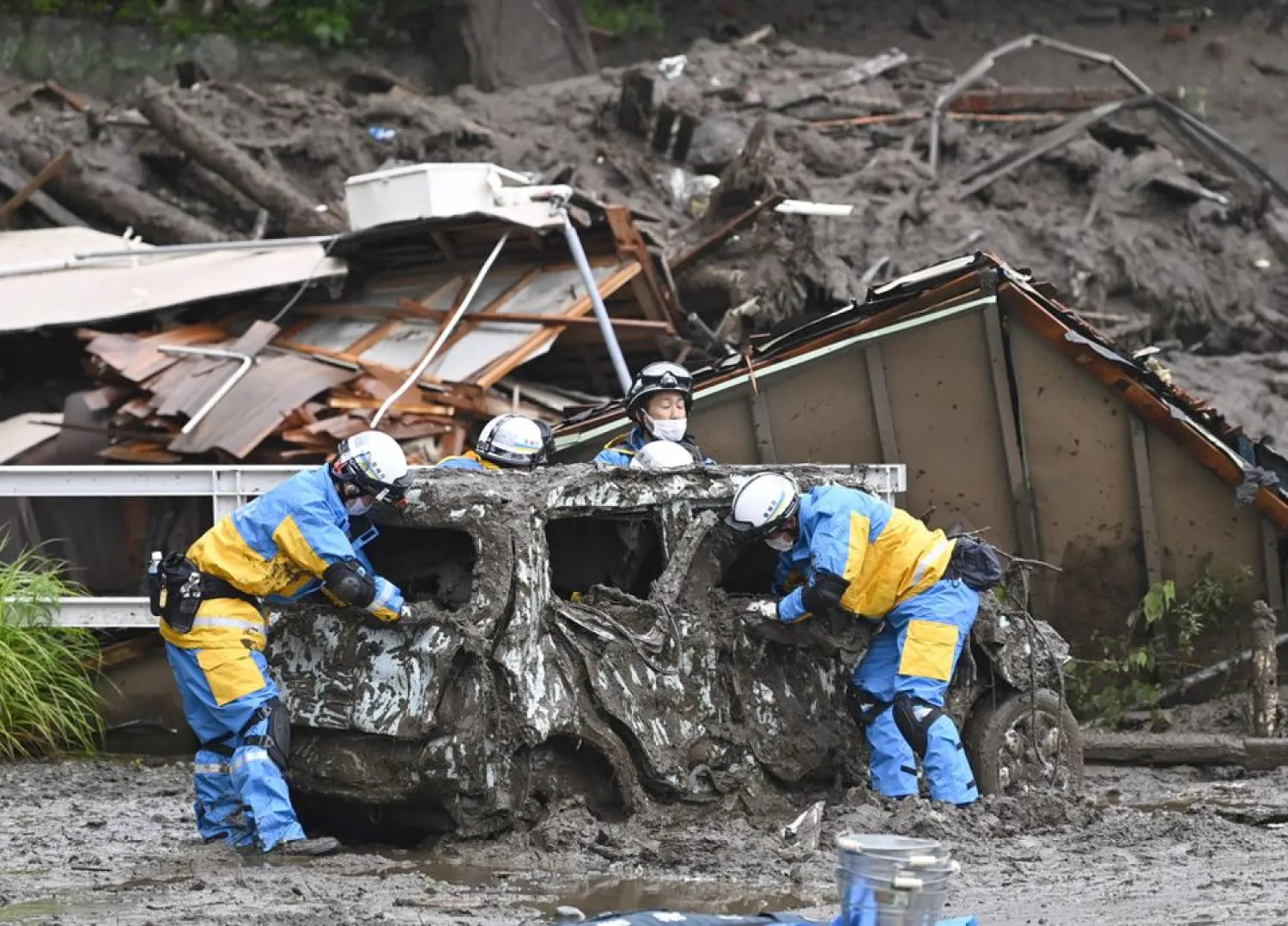 Police officers conduct search and rescue operation around a destroyed car at a mudslide site caused by heavy rain at Izusan district in Atami, west of Tokyo, Japan July 4, 2021, in this photo taken by Kyodo. Kyodo/via REUTERS