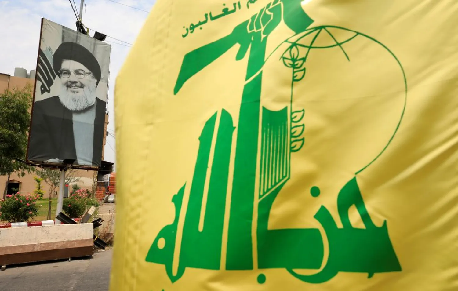 A Hezbollah flag and a poster depicting Lebanon's Hezbollah leader Hassan Nasrallah are pictured along a street, near Sidon, Lebanon July 7, 2020. REUTERS/Ali Hashisho/File Photo