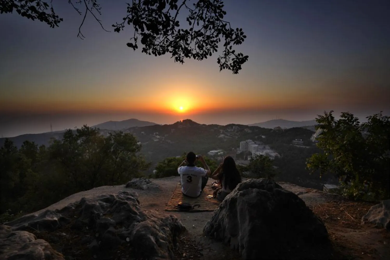 A young couple enjoy the sunset during a hike trip in Chahtoul village, in the Keserwan district, Mount Lebanon Governorate of Lebanon, Sunday, June 27, 2021. (AP Photo/Hassan Ammar)
