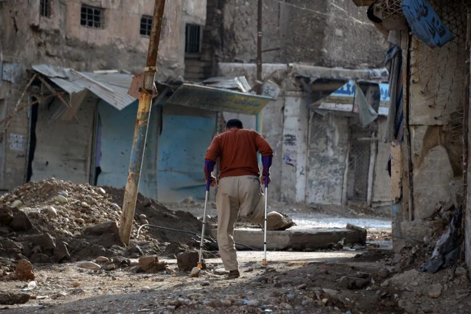 عراقي مبتور الطرف يحاول السير وسط حطام في الحي القديم بمدينة الموصل شمال العراق عام 2018 (أ.ف.ب)