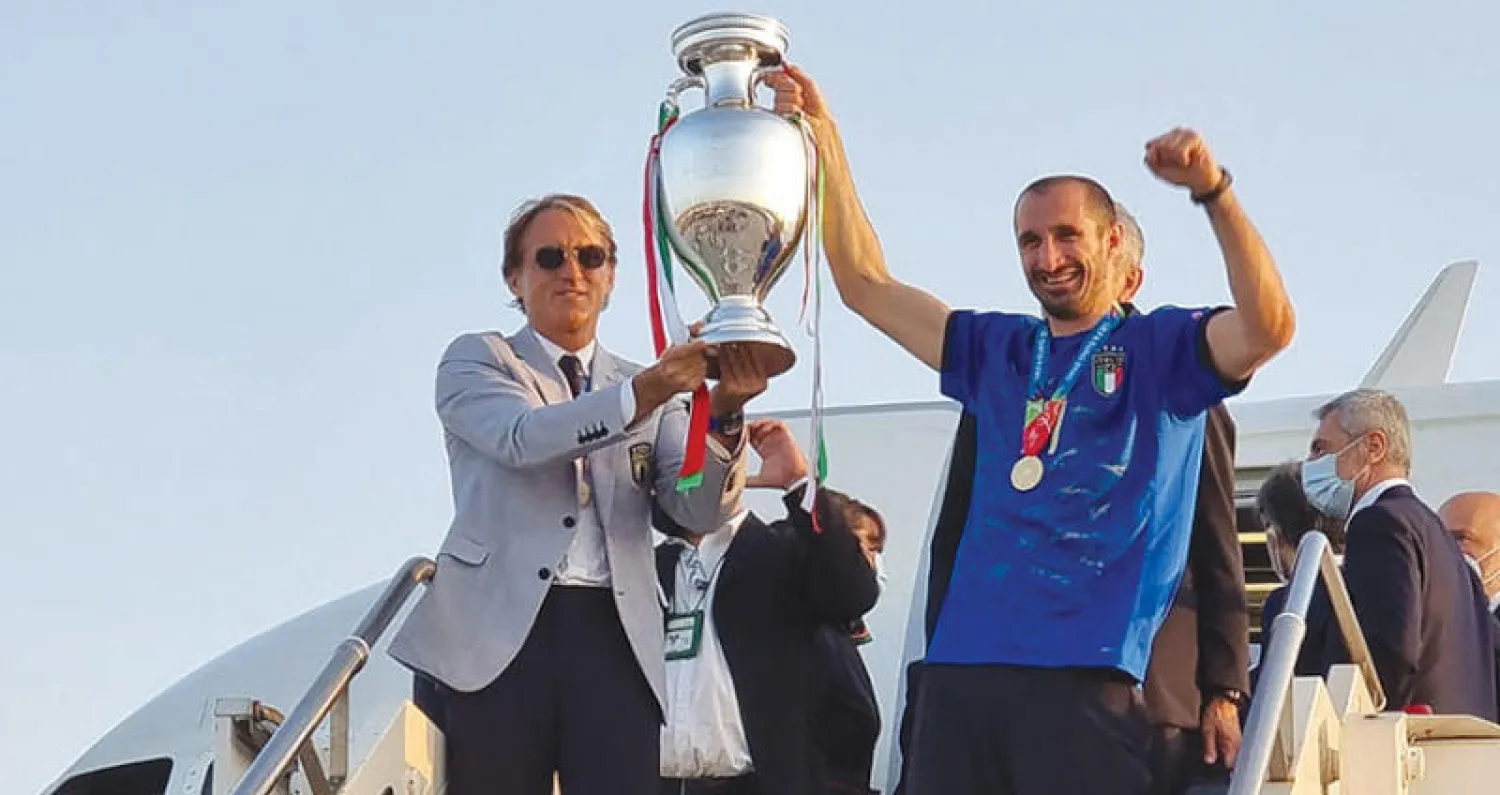 المدرب مانشيني (يسار) يشارك كيليني رفع كأس أوروبا لدى الوصول إلى مطار روما (أ.ف.ب)