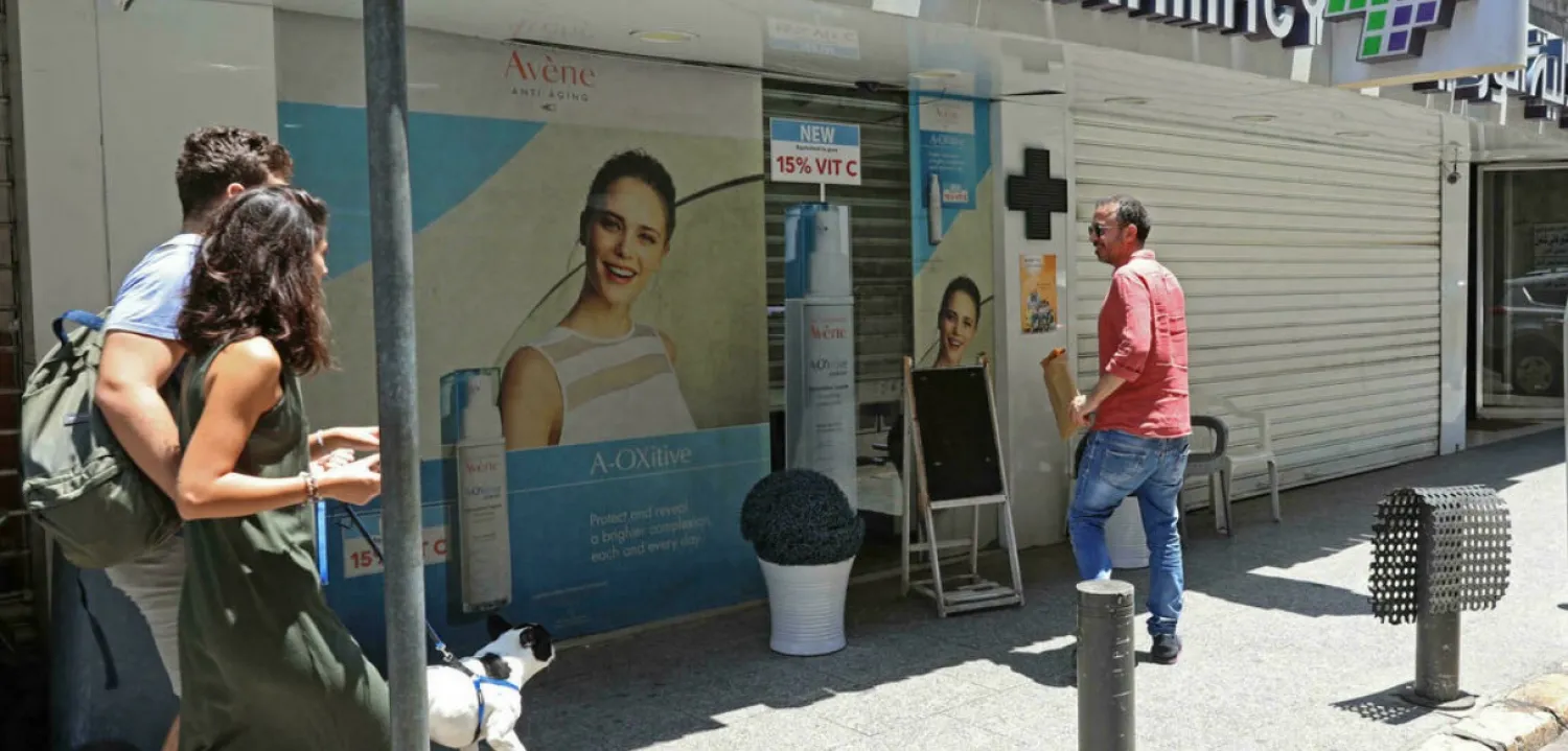 People walk in front of a shuttered pharmacy in the Lebanese capital Beirut during a nationwide strike of pharmacies in protest of a severe shortage of medicine on July 9, 2021. Anwar Amro, AFP