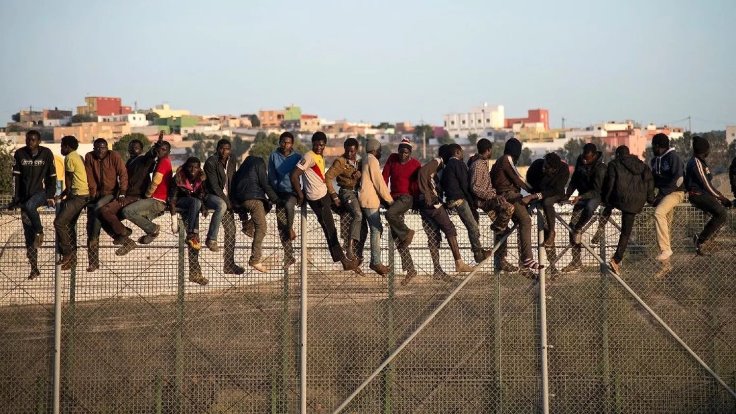 A file photo of would-be immigrants stand atop a border fence separating Morocco from the enclave of Melilla. (AFP)