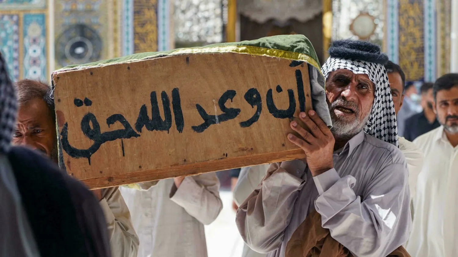 Iraqis carry coffins in Najaf on July 13, 2021 of relatives killed in a hospital fire in the city of Nasiriyah. (AFP)