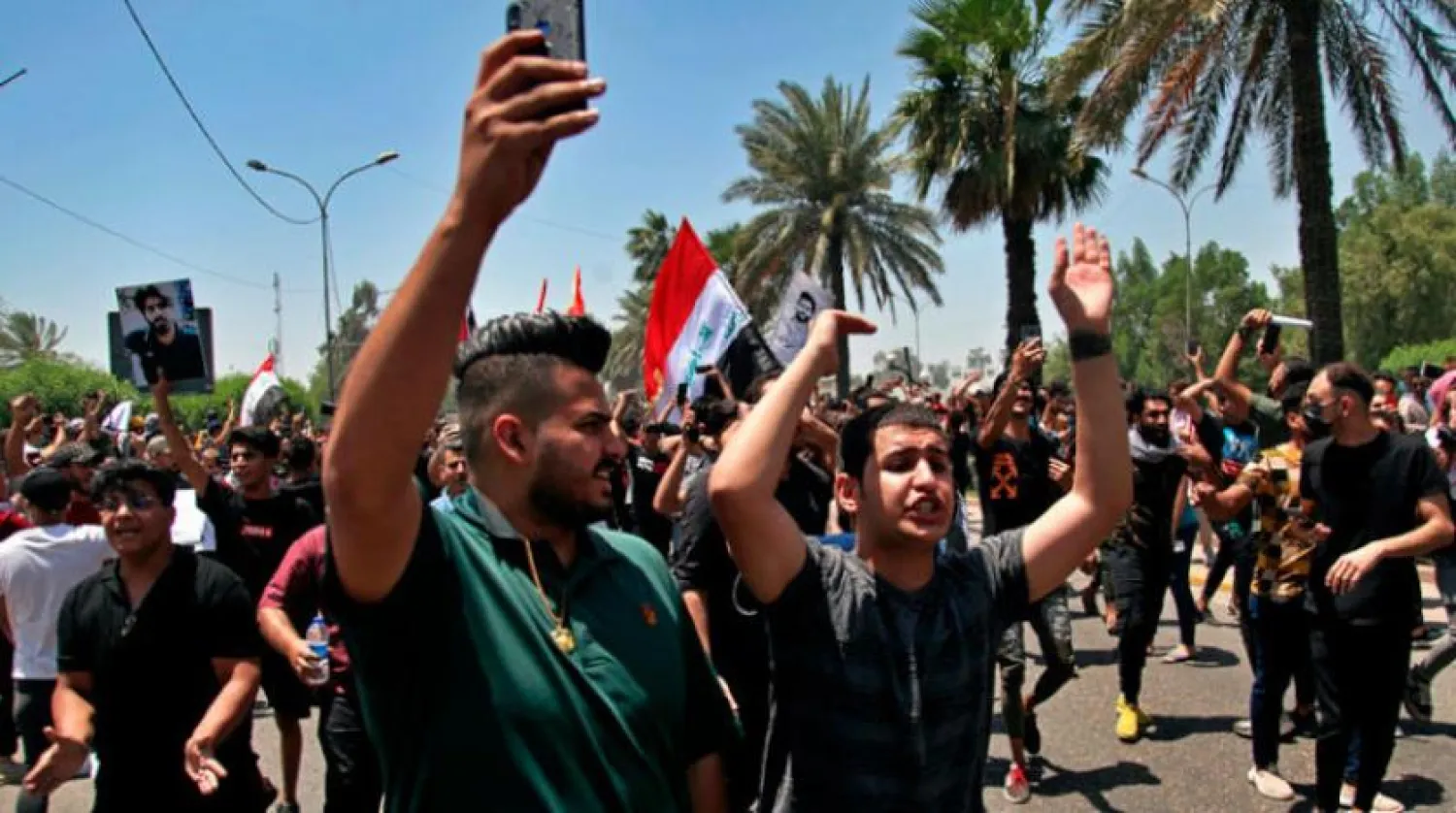 Geçtiğimiz mayıs ayında suikasta uğrayan bir aktivistin fotoğrafını taşıyan Bağdat’taki protestocular. (AP)