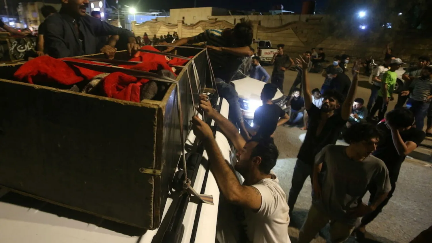 People react next to the body of a casualty outside al-Hussain coronavirus hospital after a fire, in Nasiriyah, Iraq, July 13, 2021. (Reuters)