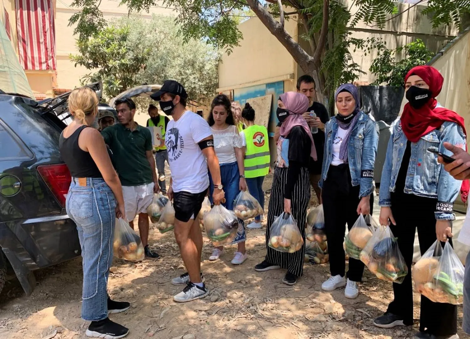 Volunteers from Base Camp, carry bags of vegetables to be distributed to people in need in Beirut, Lebanon July 1, 2021. 