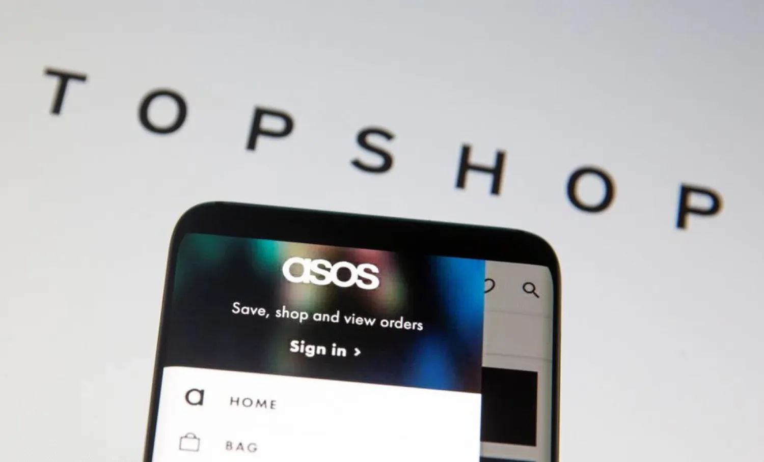 Asos logo is seen in a smartphone in front of a displayed TopShop logo in this illustration taken January 25, 2021.

