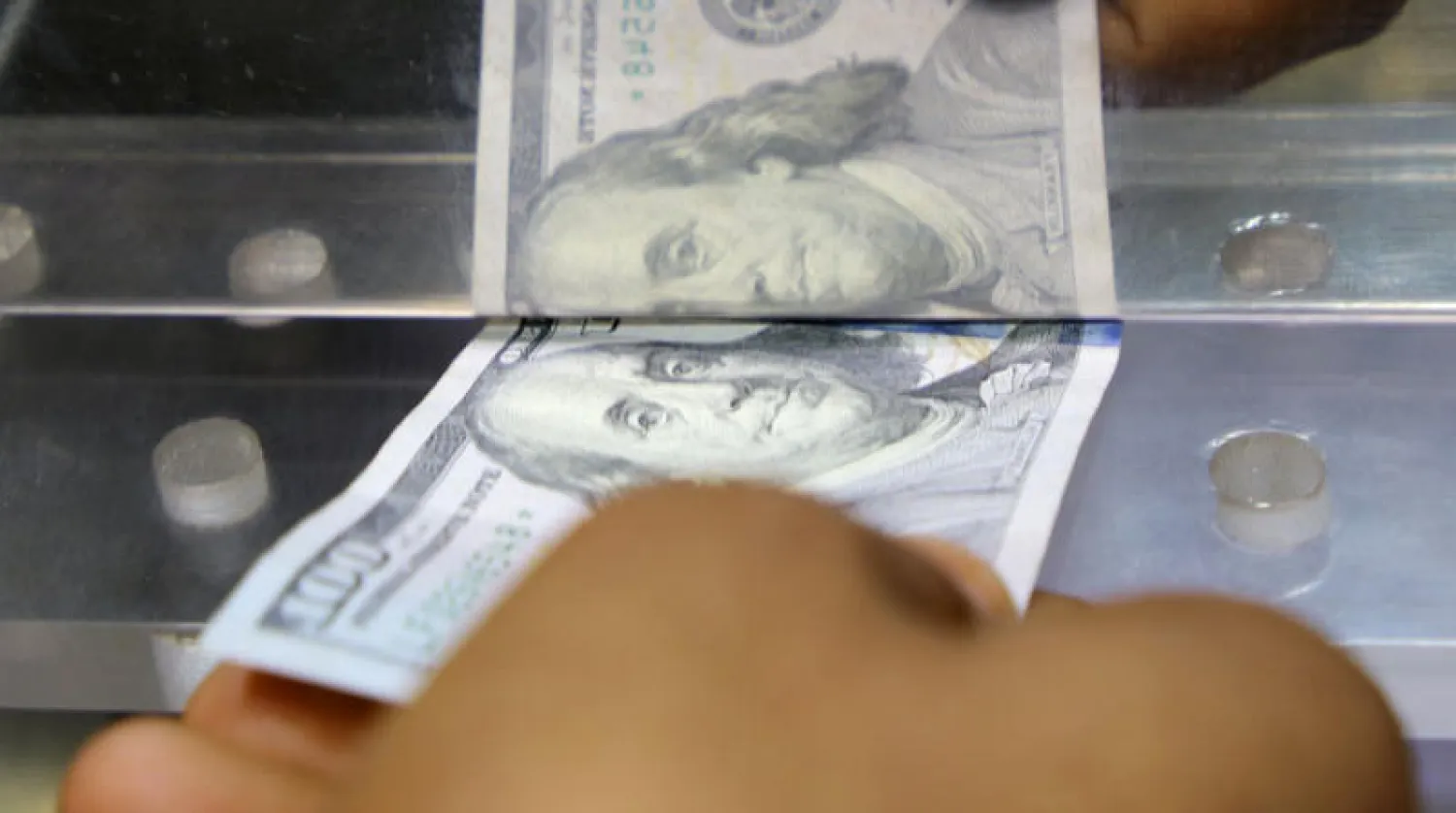 رجل يغيّر عملة بمتجر صرافة في عدن (رويترز)