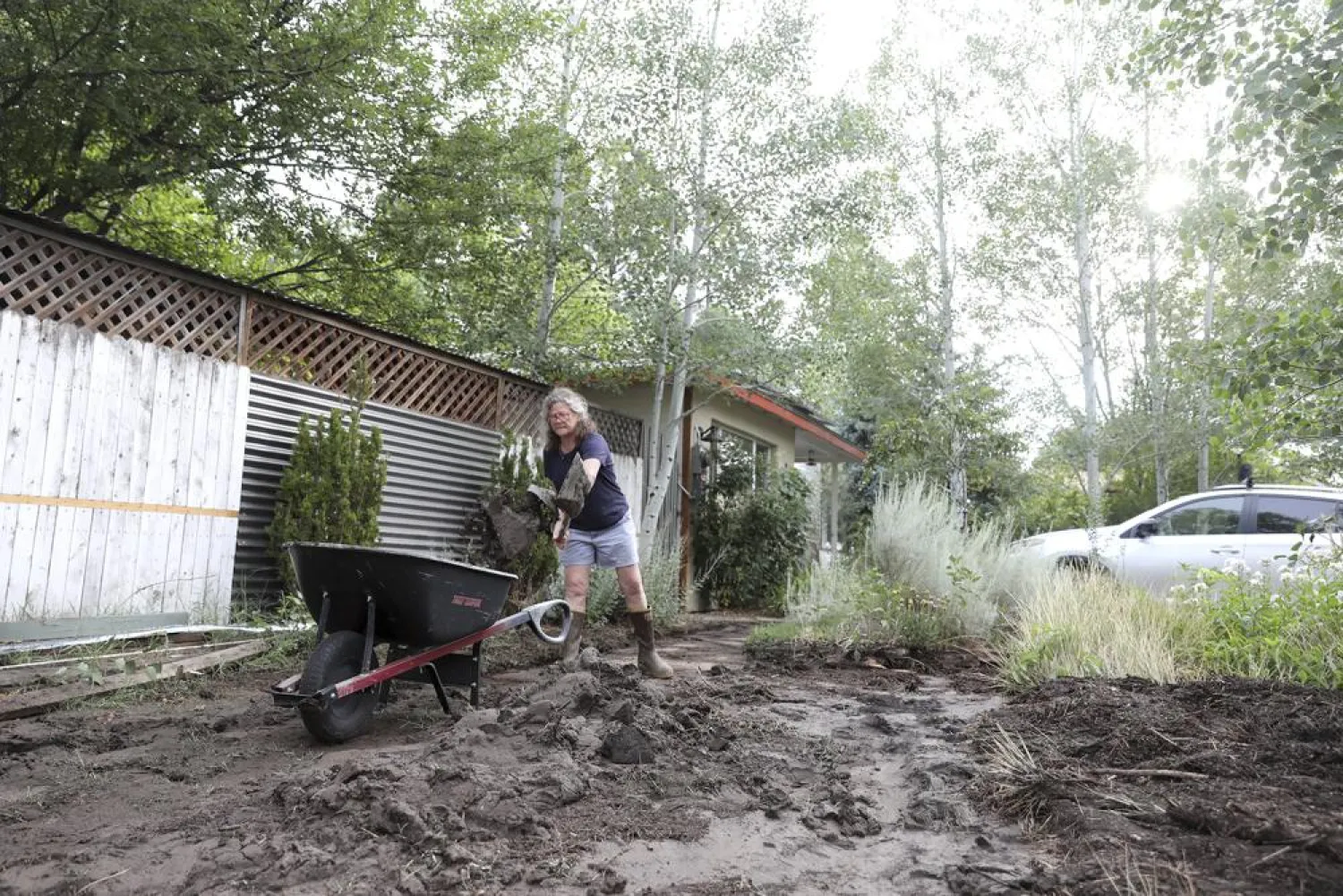 Shawn Newell digs out piles of muck from her driveway and front garden left behind by extensive flooding in Flagstaff, Ariz. on Wednesday, July 14, 2021. (Jake Bacon/Arizona Daily Sun via AP)