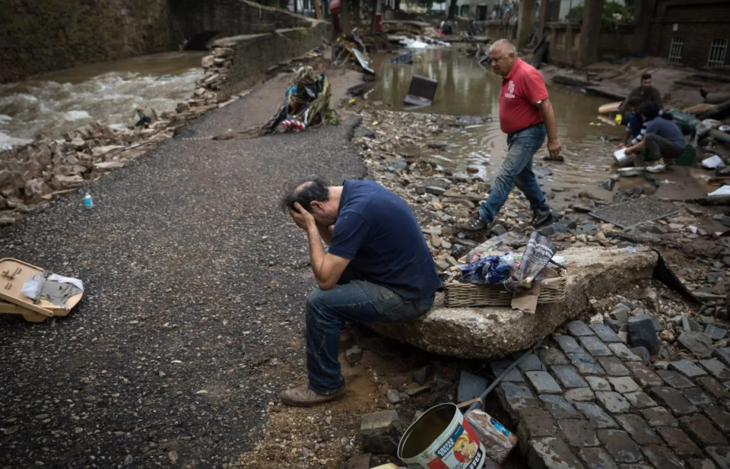 رجل يجلس مصدوما أمام مطعمه الذي تضرر في الفيضانات بألمانيا (نيويورك تايمز)