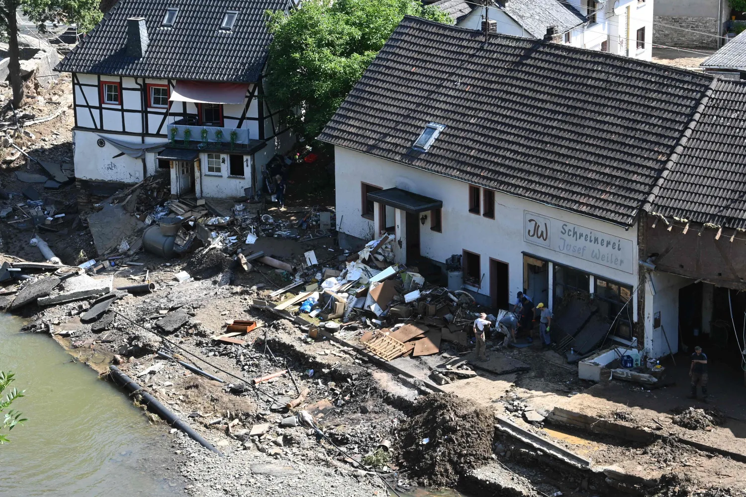 منظر أرضي يظهر الناس وهم يزيلون الأنقاض أمام ورشة نجارة في شولد غرب ألمانيا (أ.ف.ب)