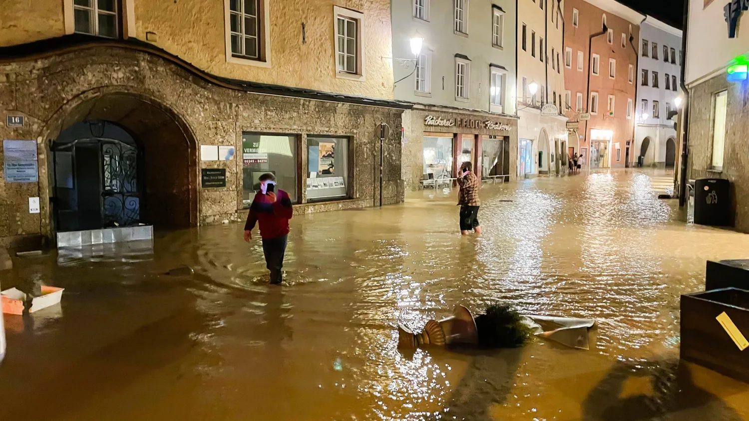 أشخاص يسيرون في المركز التاريخي الذي غمرته الفيضانات في هالين، النمسا (أ.ف.ب)
