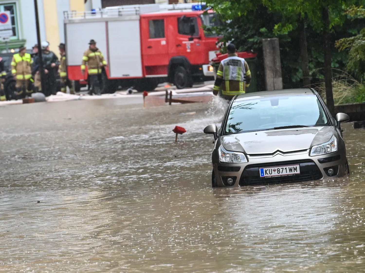 رجال الإطفاء يعملون بالقرب من شارع غمرته المياه في كوفشتاين تيرول بالنمسا (أ.ف.ب)