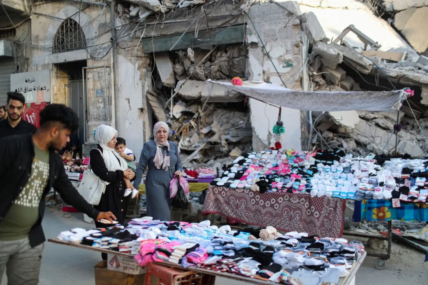 A Palestinian sells socks on a stall near the rubble of his old store that has been destroyed in an Israeli air strike, ahead of Eid Al-Adha Muslim holiday, in Gaza City, July 14, 2021. Picture taken July 14, 2021. REUTERS/Mohammed Salem


