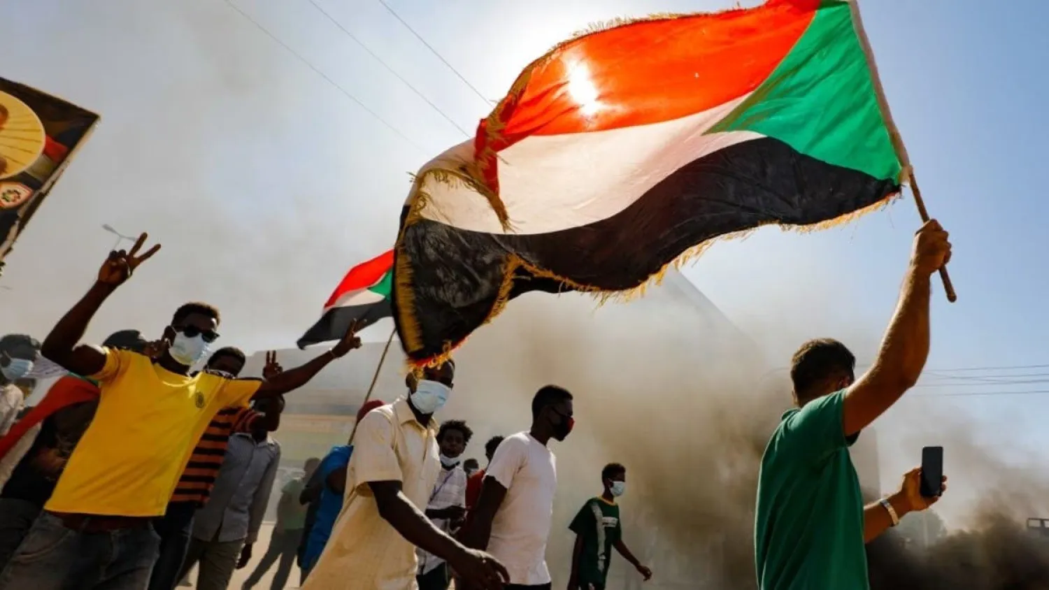 Sudanese youths wave the national flag as they rally in the streets of the capital Khartoum, chanting slogans and burning tires, on December 19, 2020. (AFP)
