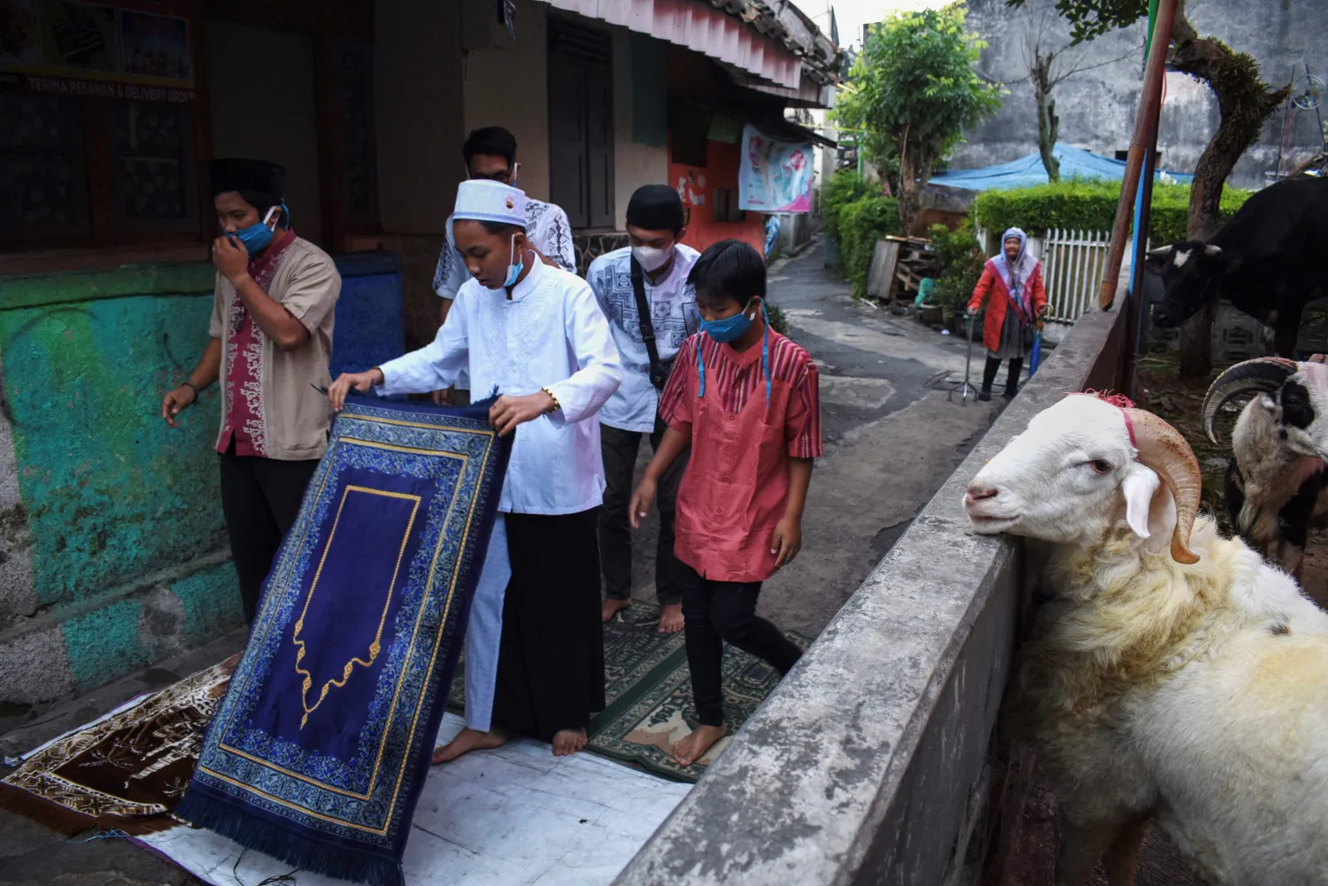 أشخاص يتجمعون للصلاة بجانب الماعز للتضحية بها في باندونغ بإندونيسيا (أ.ف.ب)