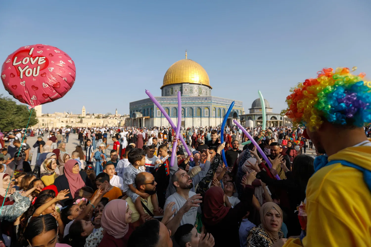 رجل يرتدي زي مهرج ويوزع البالونات على المصلين في المسجد الأقصى (أ.ف.ب)