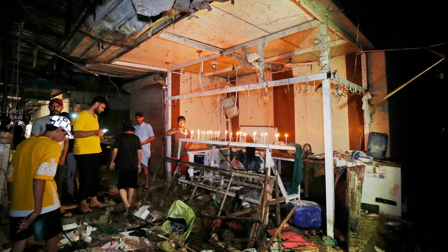Iraqis light candles at the site of the explosion in a popular market in the neighborhood of Sadr City, east of Baghdad. (AFP)