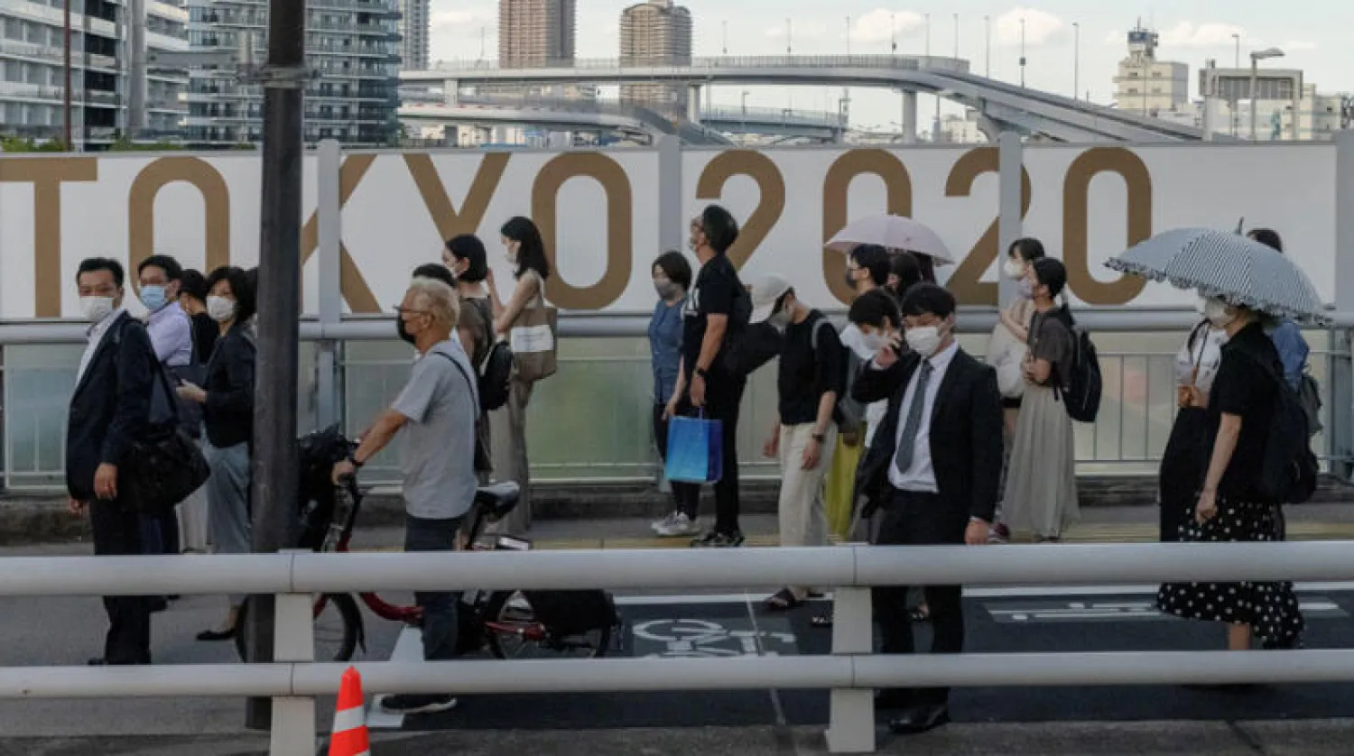 مواطنون أمام شعار «أولمبياد طوكيو» عشية افتتاح الألعاب مع استمرار تفشي «كورونا» (رويترز)