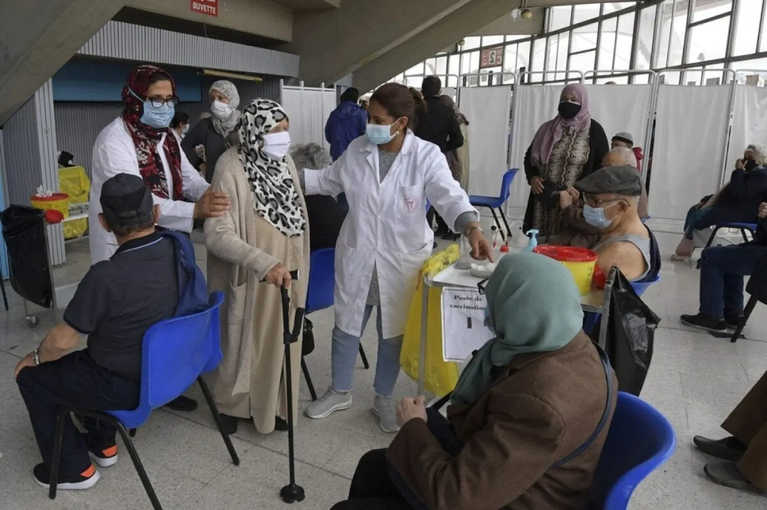 Tunisian healthcare workers assist an elderly woman during inoculation at El-Menzah sports hall in Tunisia’s capital Tunis on May 3, 2021. (Getty Images)