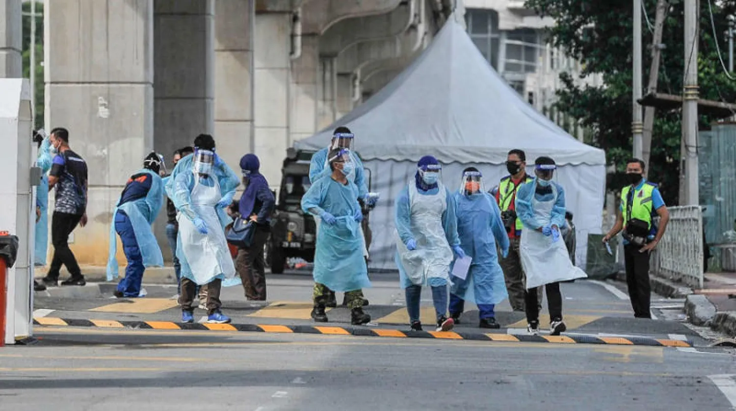 موظفون يتفقدون منطقة سكنية معزولة في بيتالينغ جايا بماليزيا الأحد الماضي (د.ب.أ)