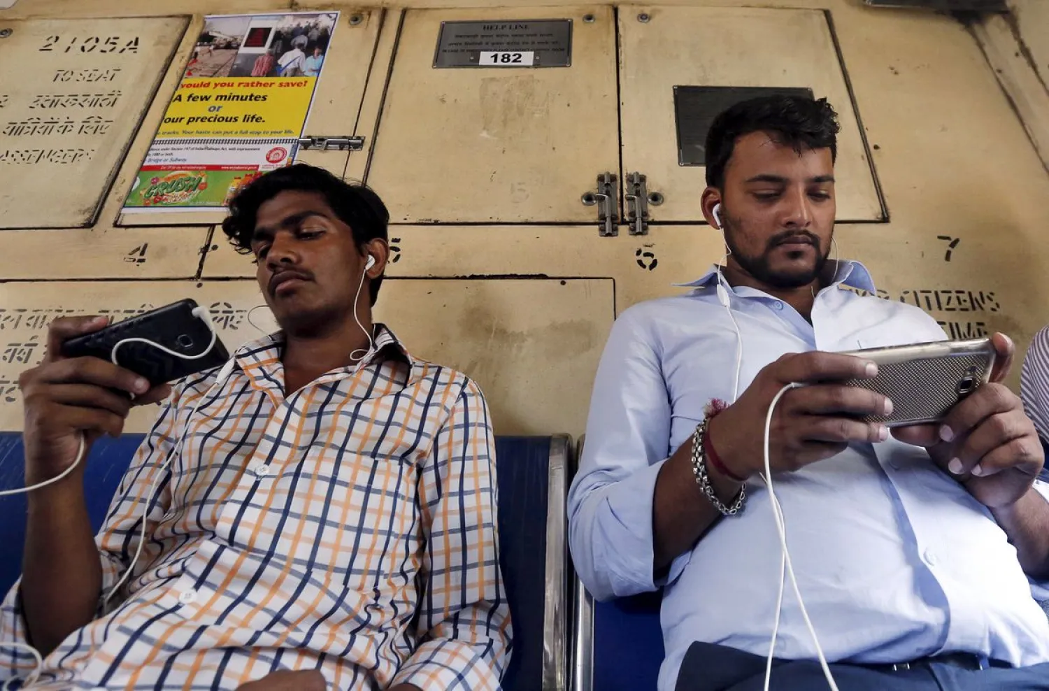 Commuters watch videos on their mobile phones as they travel in a suburban train in Mumbai, India, April 2, 2016. REUTERS/Shailesh Andrade/File Photo

