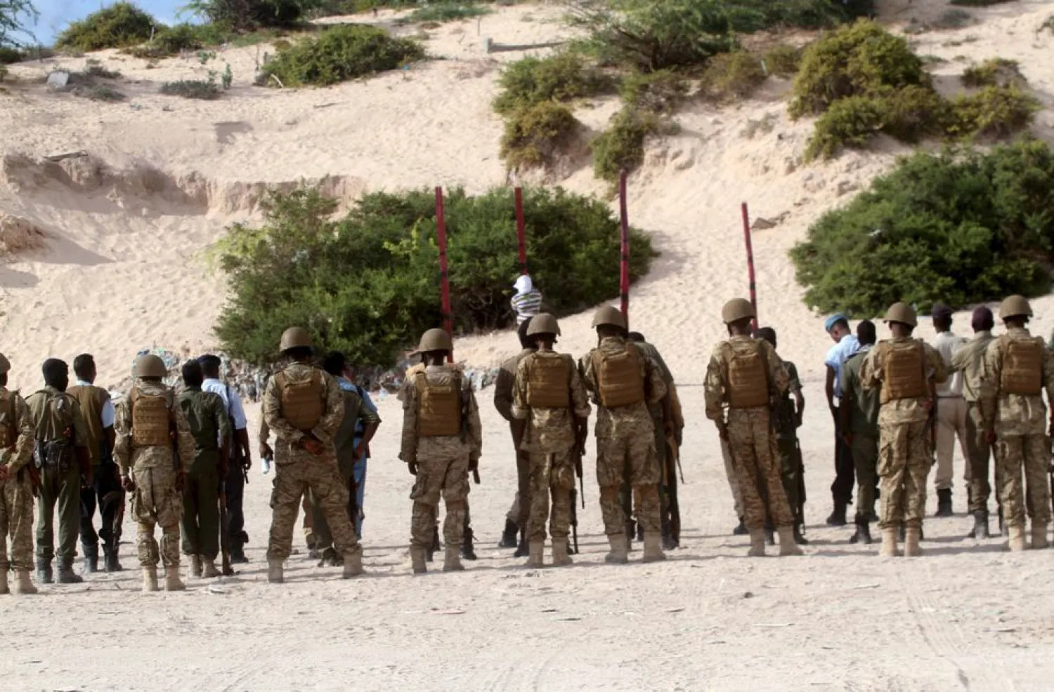 Somalia soldiers and policemen look on as Hassan Hanafi, a former media officer for Al Shabaab, stands tied to a pole before his execution by shooting at close range on a field in General Kahiye Police Academy in Somalia's capital Mogadishu, on April 11, 2016. REUTERS/Ismail Taxta