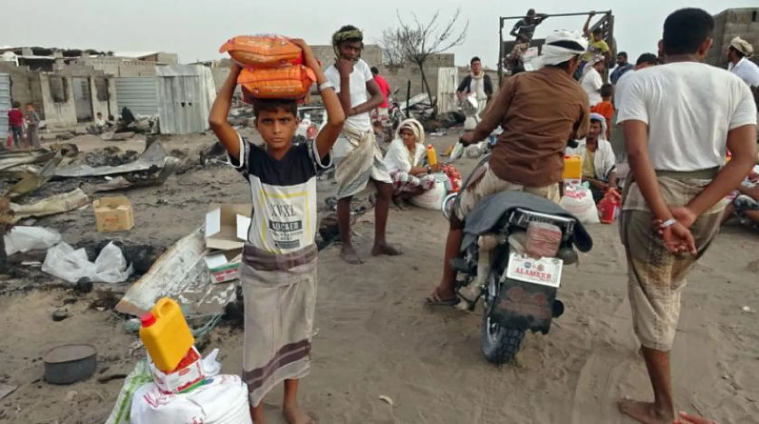 Internally displaced Yemenis whose camp was ravaged by fire 2 days earlier receive food aid in the village of al-Durayhimi, on the southern edge of the flashpoint Red Sea port city of Hodeidah, on July 19, 2021. (Photo by Khaled Ziad / AFP)