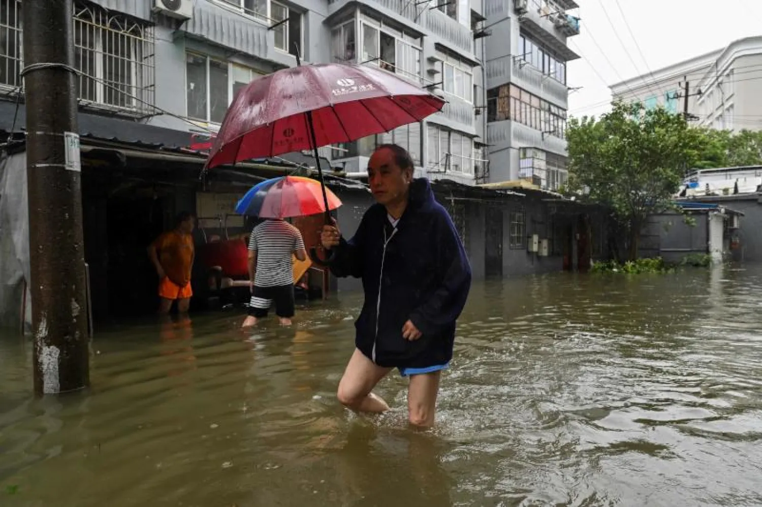 رجل يسير وسط مياه الفيضانات شرق الصين (أ.ف.ب)
