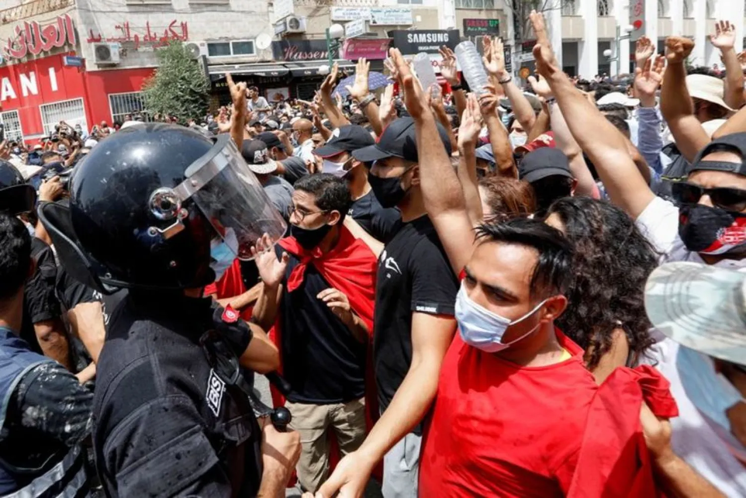 Demonstrators gather in front of police officers standing guard during an anti-government protest in Tunis, Tunisia, July 25, 2021. (Reuters)