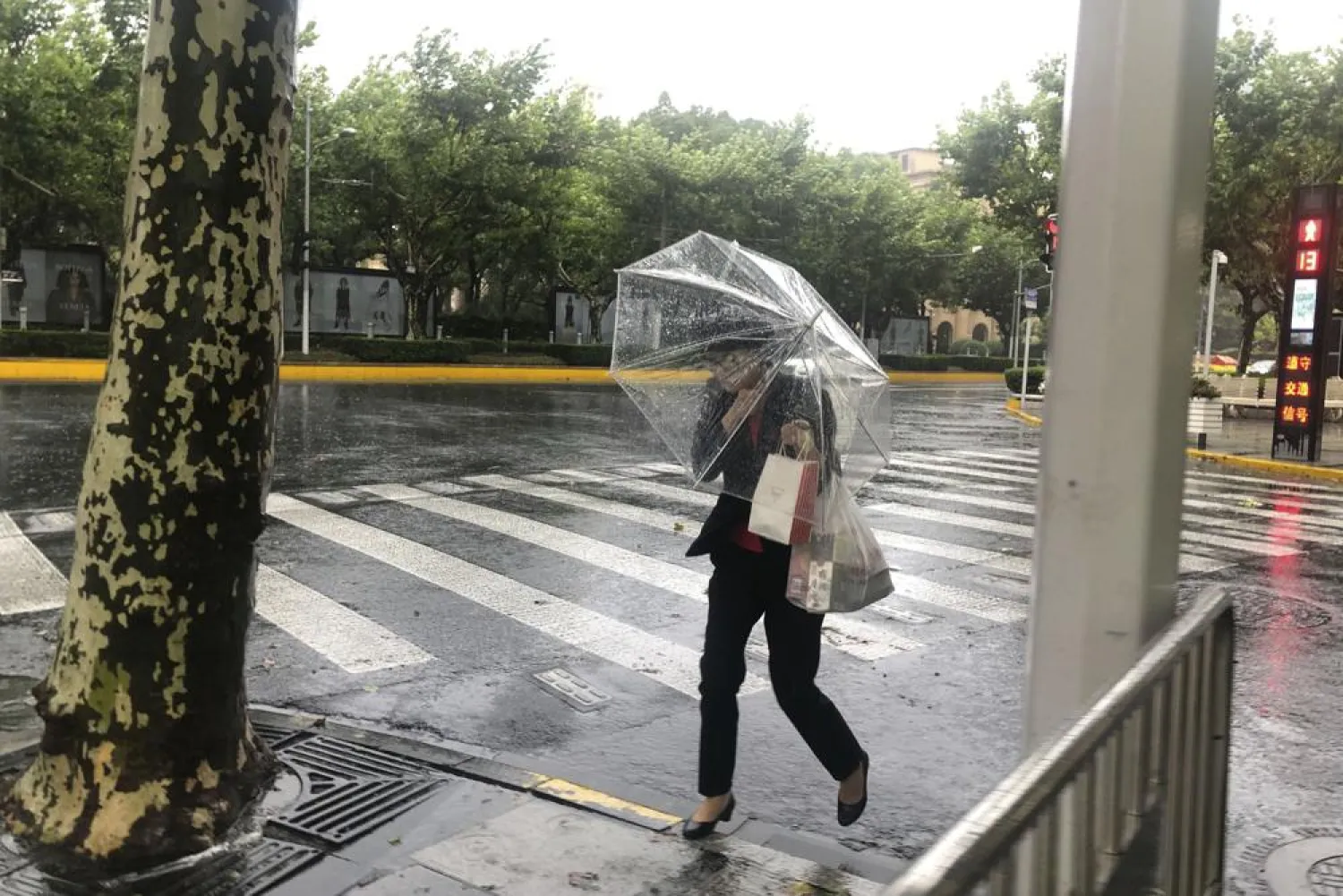 A woman carrying an umbrella braces against the wind and rain as Typhoon In-fa sweeps through Shanghai in China Sunday, July 25, 2021. (AP Photo/Chen Si)
