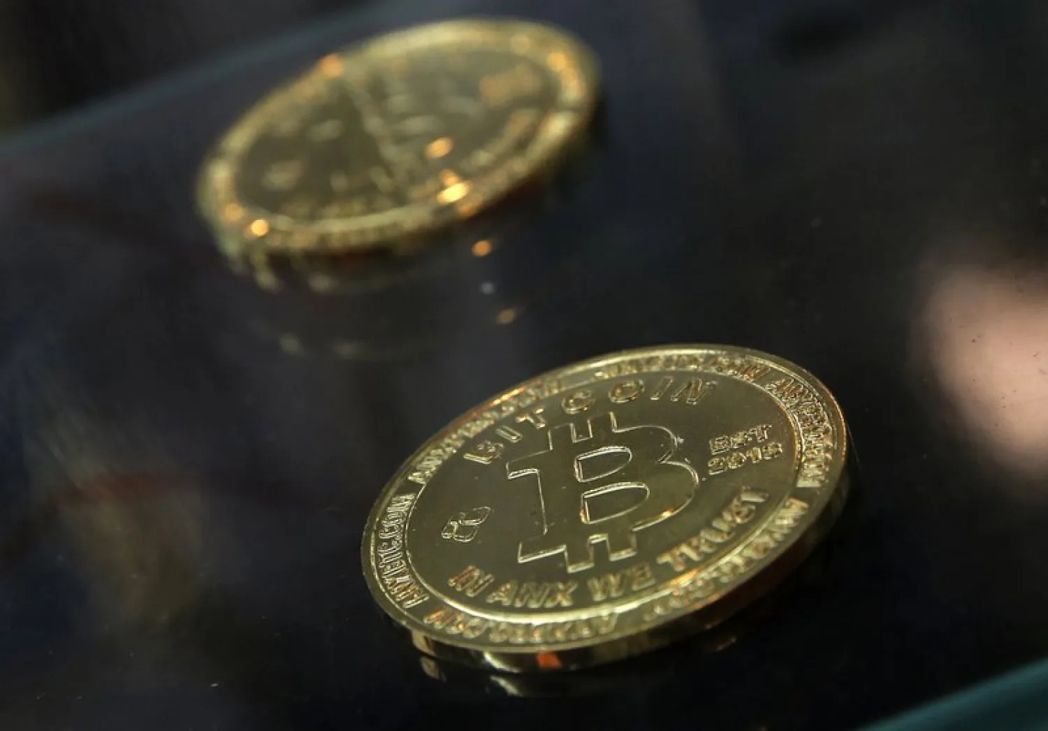 FILE- In this Dec. 8, 2017, file photo, coins are displayed next to a Bitcoin ATM in Hong Kong. (AP Photo/Kin Cheung, File)
