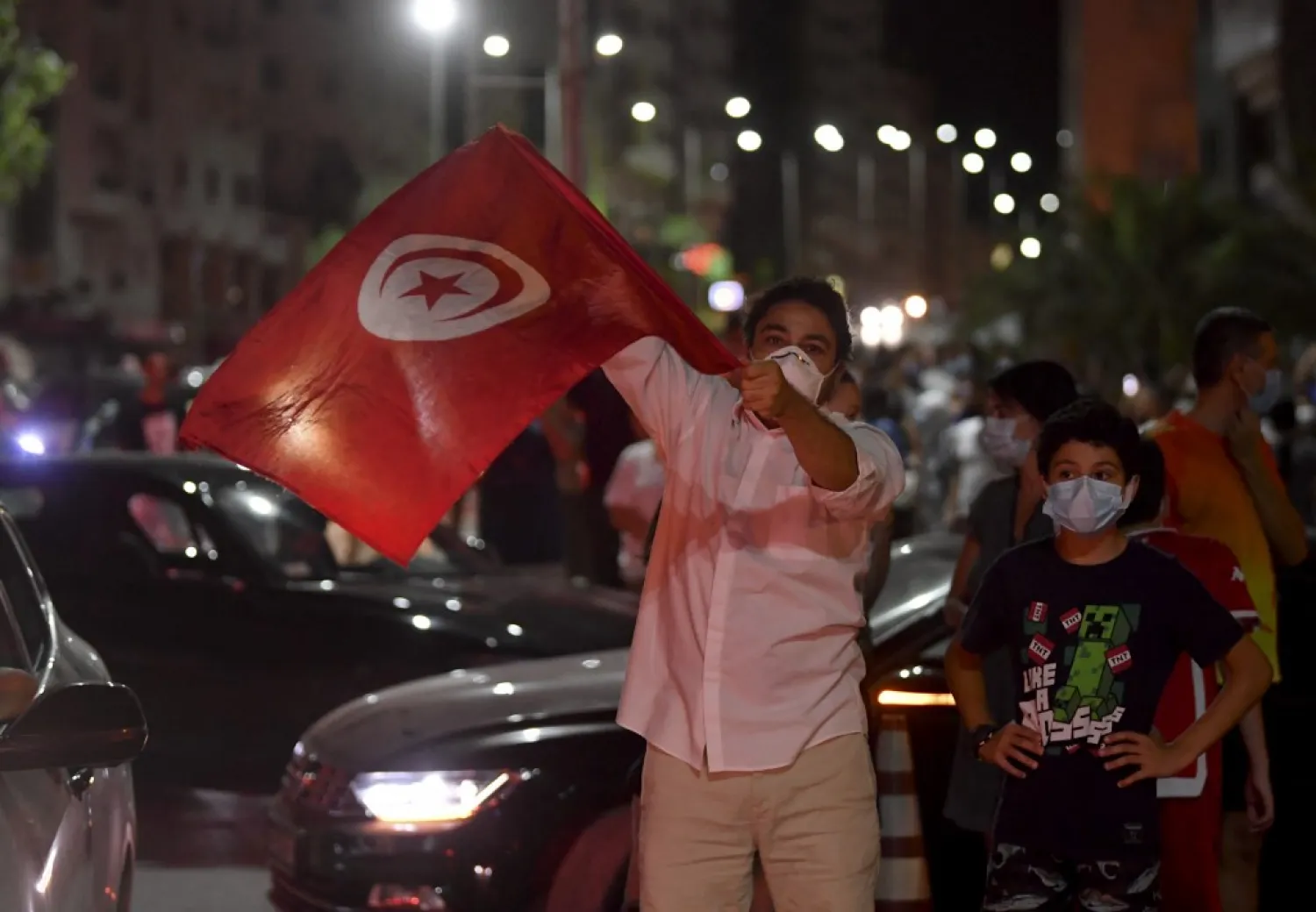People celebrate in the street after Tunisian President Kais Saied announced the dissolution of parliament and Prime Minister Hichem Mechichi’s government in Tunis on July 25, 2021. (AFP)