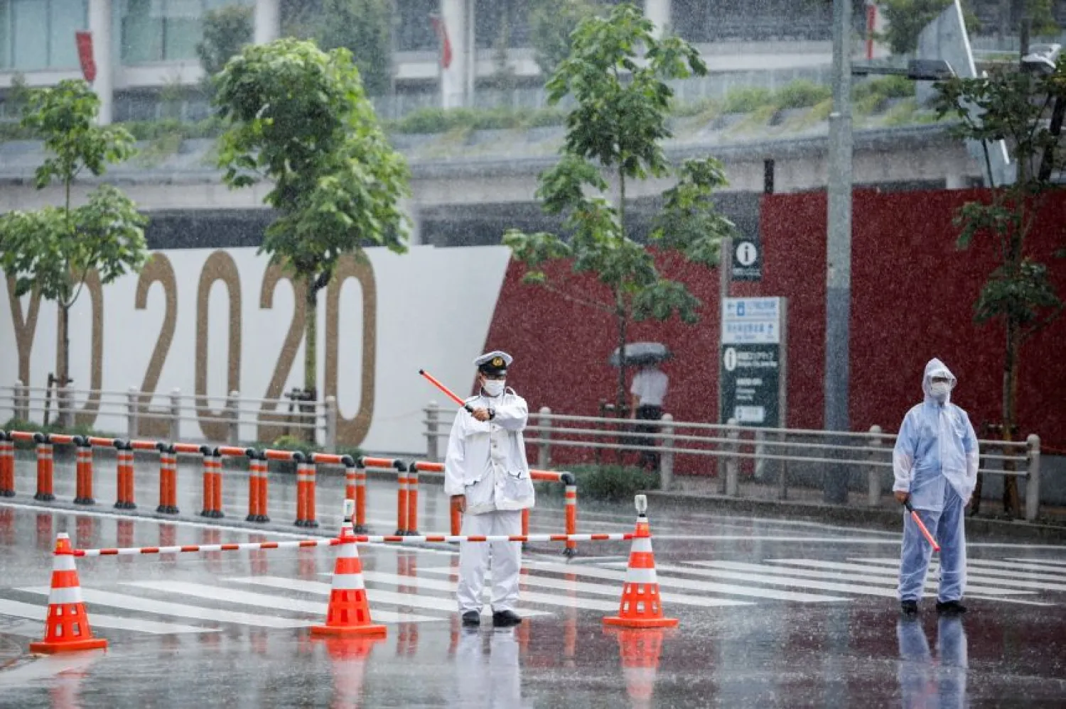 Traffic policemen control the traffic in front of the Olympic stadium in the rain caused by tropical storm Nepartak in Tokyo on July 27, 2021.PHOTO: REUTERS