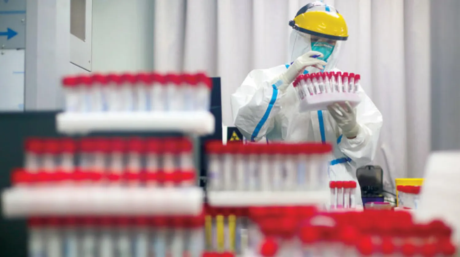 عامل مختبر يحلّل نتائج فحوص «كورونا» في نانجينغ بالصين (رويترز)