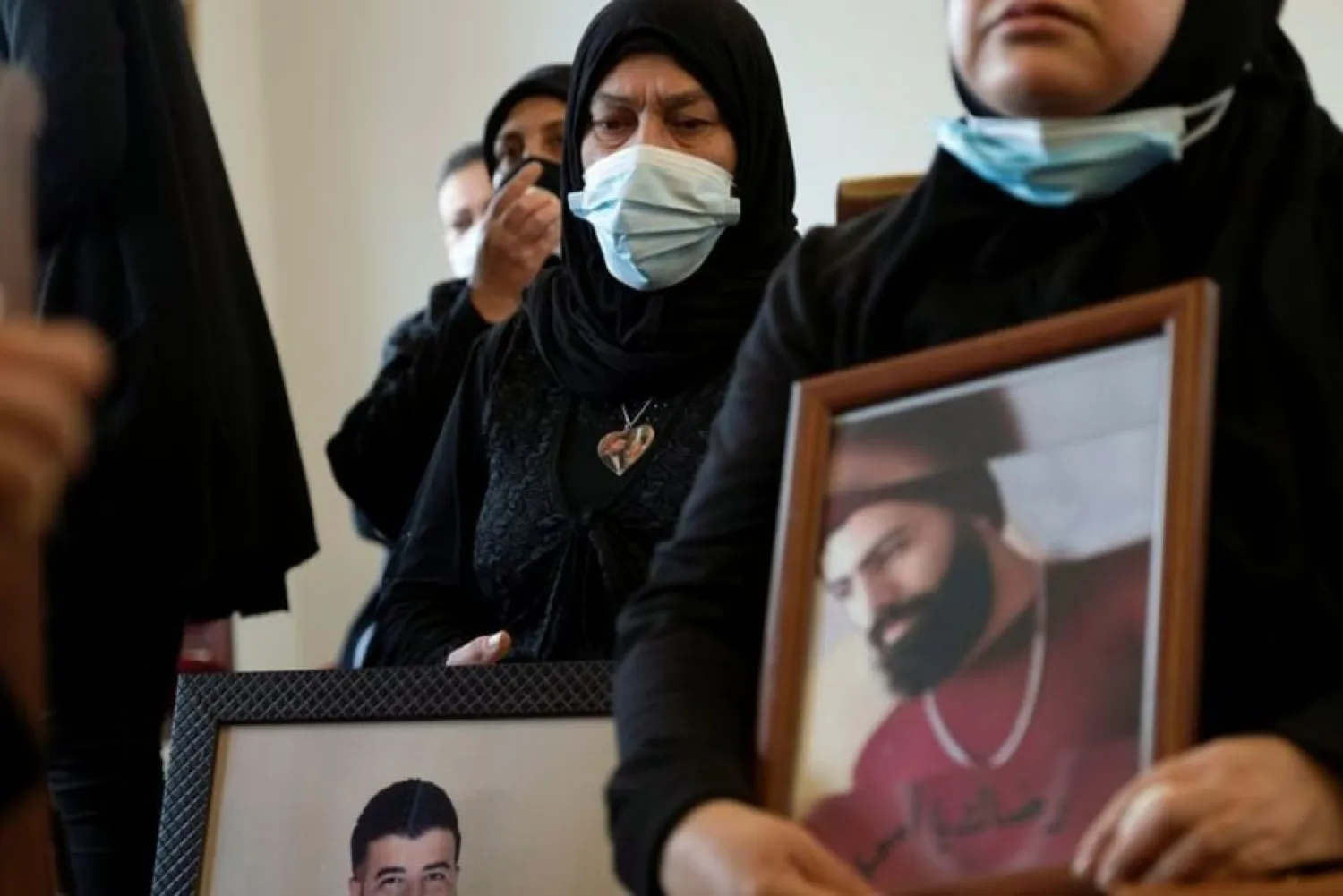 Relatives of victims of Beirut port explosion, hold their pictures during a ceremony in Beirut, Lebanon March 20, 2021. (Reuters)