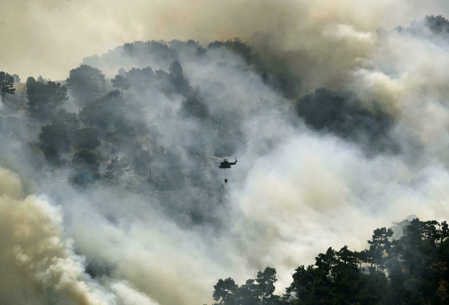 A Lebanese army helicopter drops water on a huge forest fire in the remote Akkar region of the north JOSEPH EID AFP
