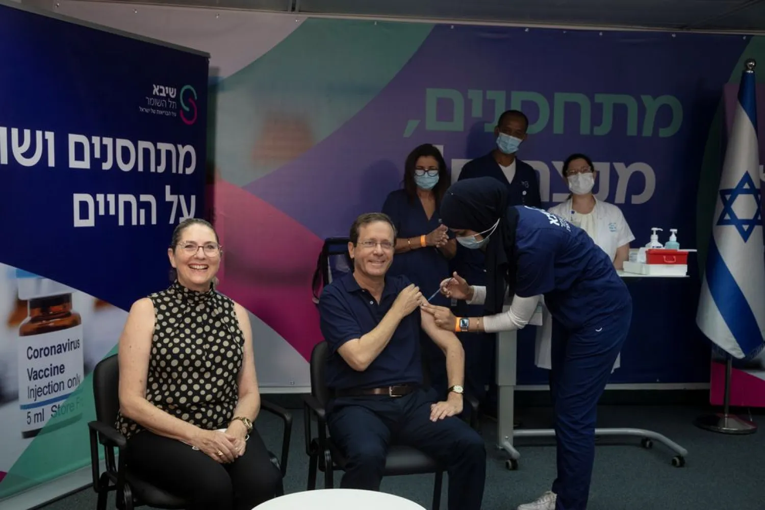Israeli President Isaac Herzog receives a third dose of coronavirus disease (COVID-19) vaccine while his wife, Michal, reacts, at Sheba Medical Center in Ramat Gan, Israel, July 30, 2021. Maya Alleruzzo/Pool via REUTERS