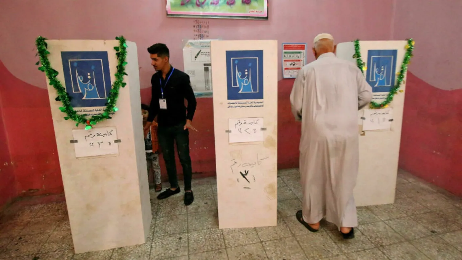 An Iraqi man (R) walks toward a voting booth at a polling station in the southern city of Basra on May 12, 2018. (AFP)