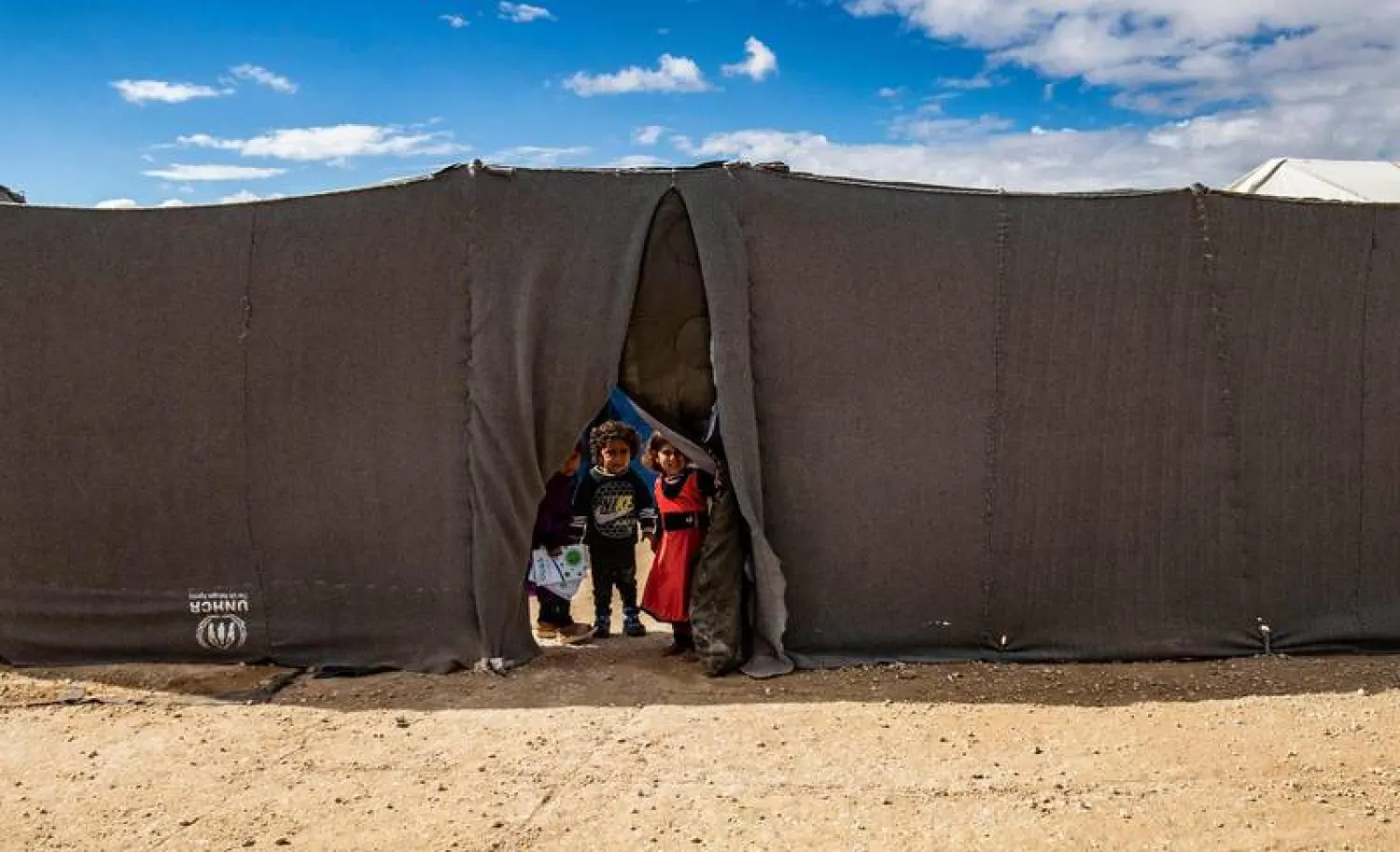 Children peek through the opening of a tent at the Kurdish-run Al-Hol camp which holds suspected relatives of ISIS fighters, in the northeastern Syria. (AFP)