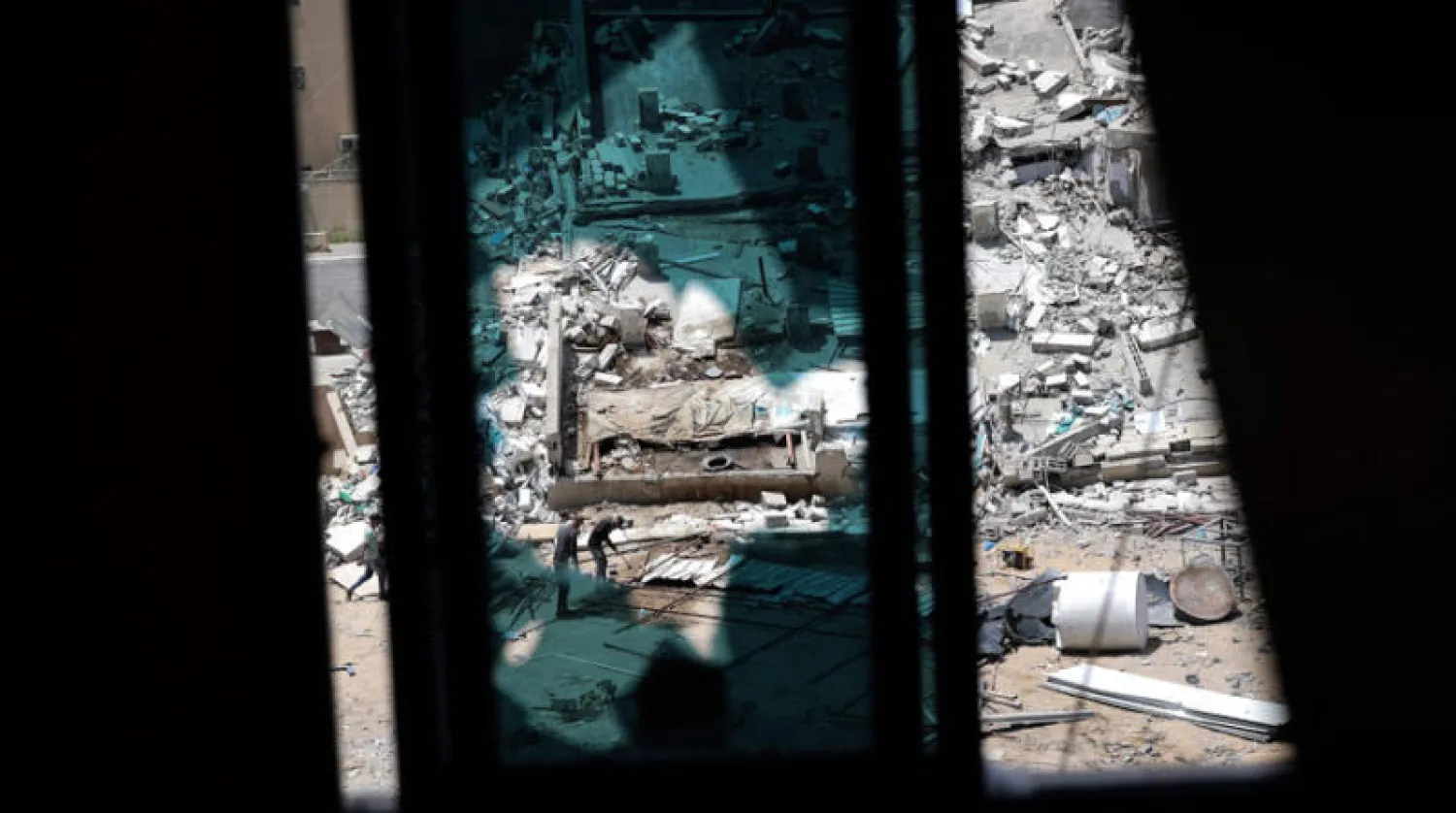 عمال يزيلون ركام الأبنية في حي الرمال وسط غزة (أ.ف.ب)