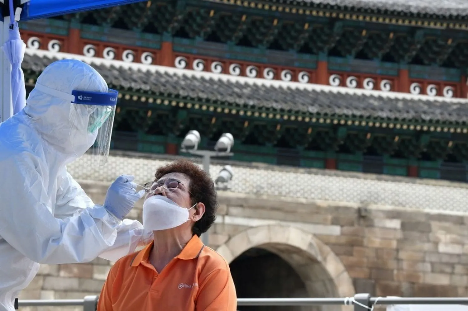A health care worker takes test samples for the Covid-19 from a man at a temporary virus testing station near Namdaemun in Seoul. (AFP file photo)