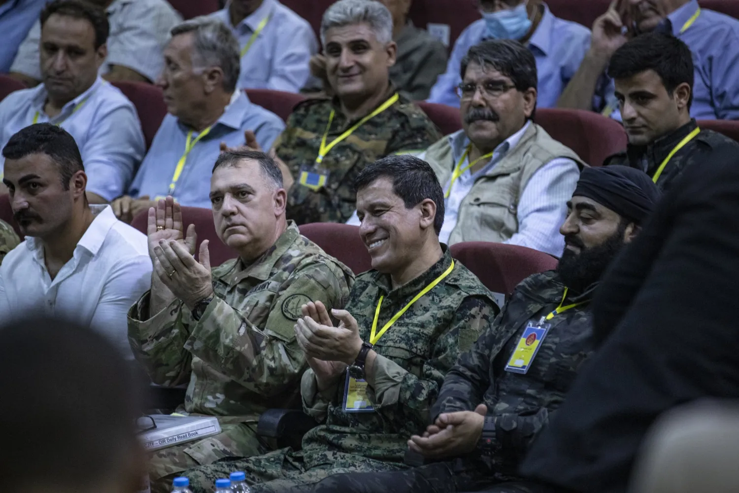 US Commander of the Combined Joint Task Force Paul T. Calvert (front C L) and Commander-in-chief of the Syrian Democratic Forces (SDF) Mazloum Abdi (front C R) attend the yearly SDF meeting in Syria's northeastern city of Hasakah on August 1, 2021. (Photo by Delil SOULEIMAN / AFP)