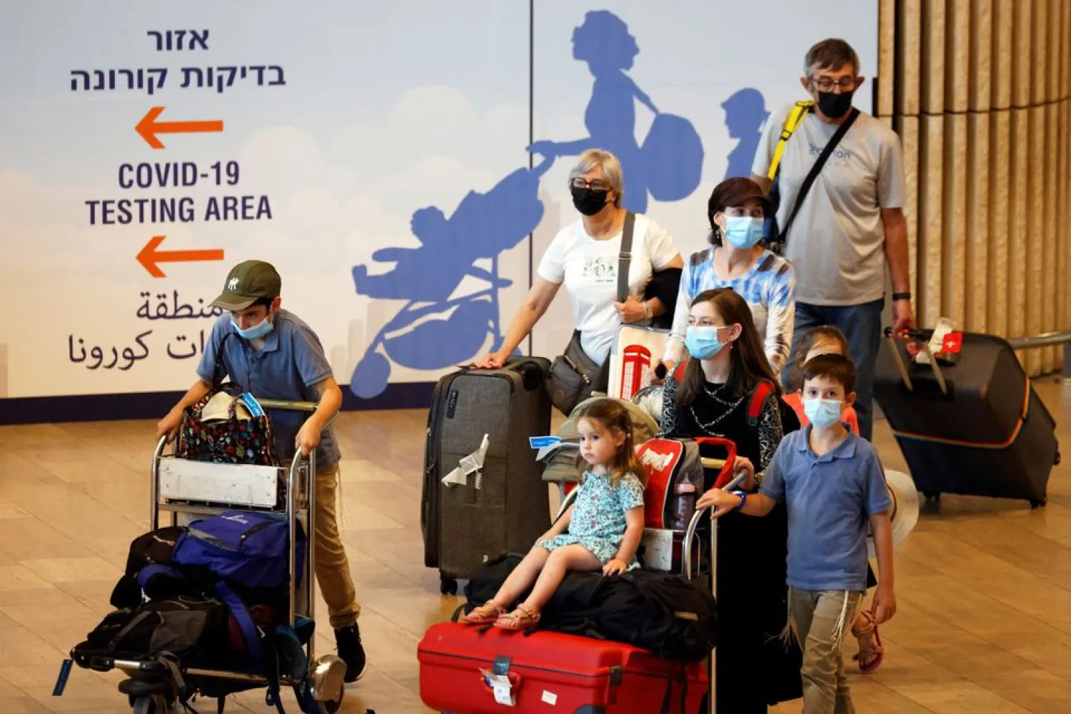 Travelers carry their luggage at the arrivals terminal in Israel's Ben Gurion International Airport, amid a spread of the Delta variant of the coronavirus disease (COVID-19), near Tel Aviv. (Reuters)