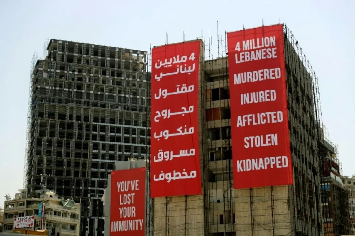Banners hang on a building damaged during last year’s port blast on August 4, 2021, as Lebanon marks a year since a cataclysmic explosion ravaged the capital Beirut. (AFP)