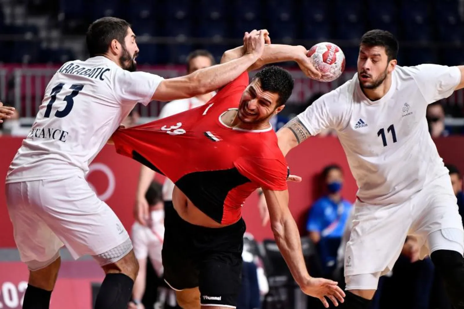 الظهير الأيسر المصري يحيى الدرع (وسط) يحاول التسديد مع عرقلة قلب الدفاع الفرنسي نيكولا كاراباتيتش (يسار) واللاعب المحوري نيكولاس تورنات خلال المباراة (أ.ف.ب)