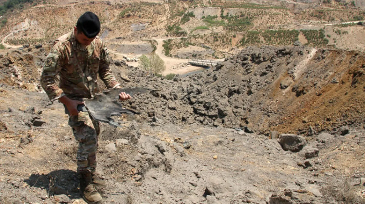 جندي لبناني يحمل بقايا قذيفة سقطت في منطقة الجنوب بعد الغارة الإسرائيلية أمس (رويترز)