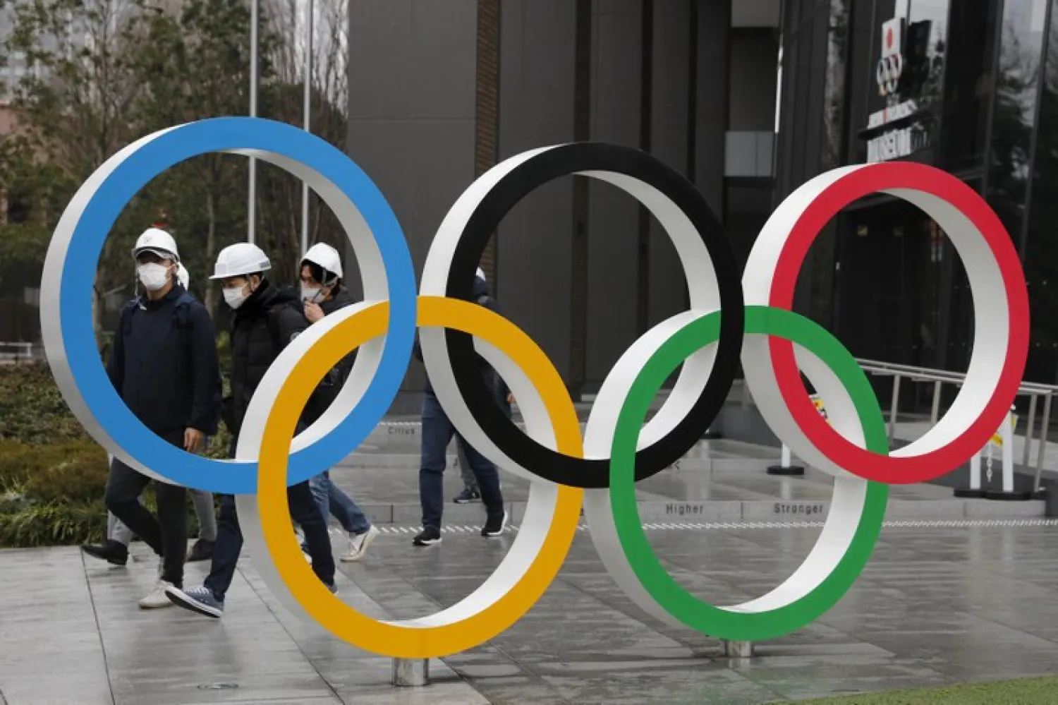 FILE - In this March 4, 2020, file photo, people wearing masks walk past the Olympic rings near the New National Stadium in Tokyo. (AP Photo/Jae C. Hong, File)


