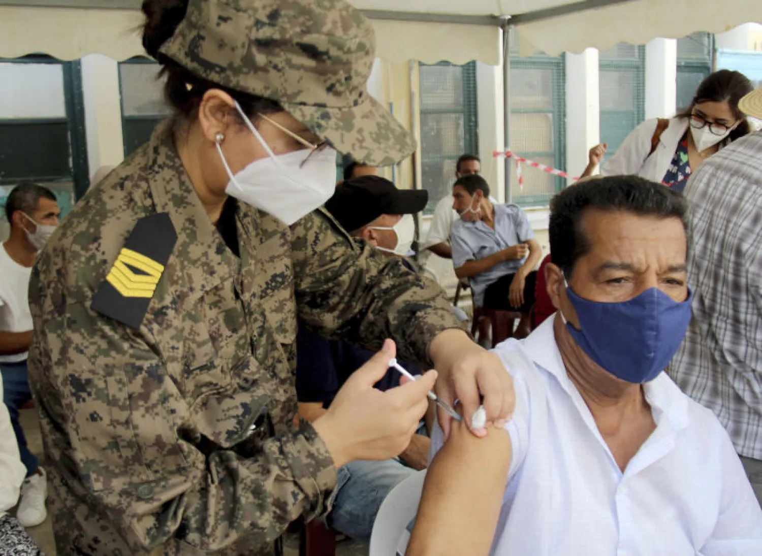 جندية تونسية تعطي جرعة لقاح لأحد المواطنين (أ.ب)